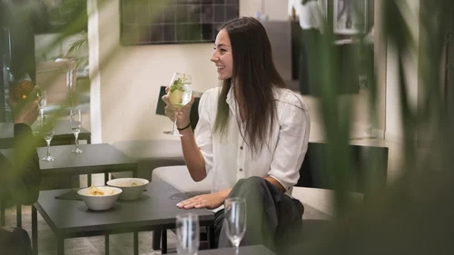 Smiling woman holding a drink while seated at a restaurant table