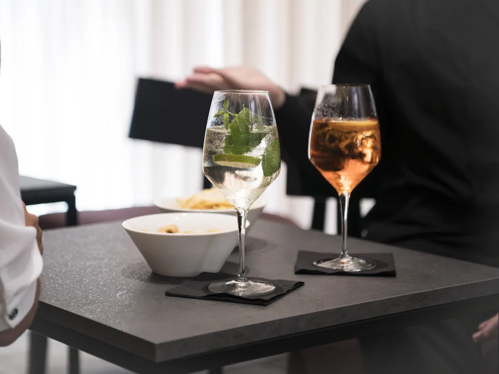 Two drinks, one with mint and lime, served with small bowls on a table