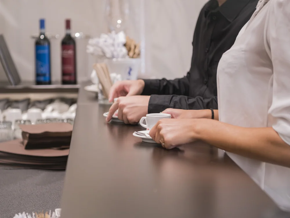Staff at a café counter with a small cup of coffee and stacked saucers