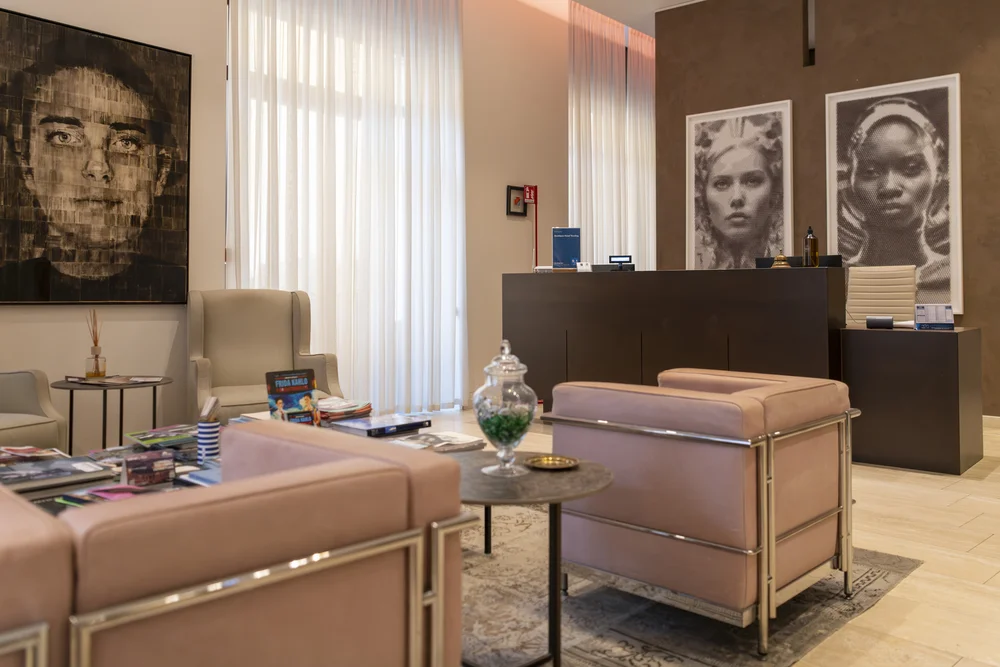 Hotel lounge with upholstered armchairs, coffee tables, large portrait artworks and a reception desk