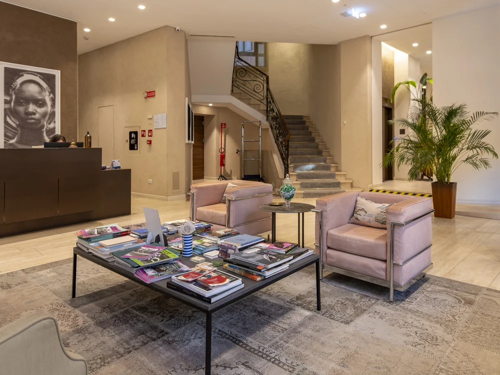 Hotel lobby with a reception desk, lounge seating, a staircase and glass doors
