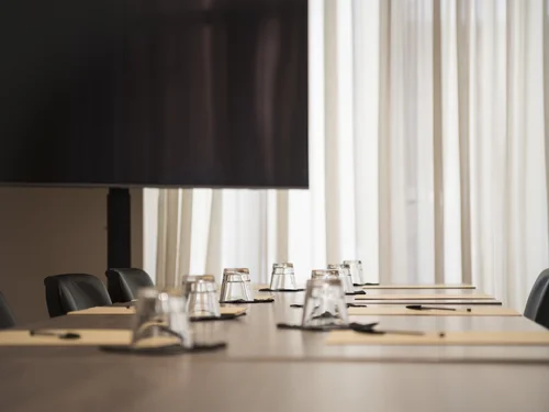 Conference room with a long table, chairs, glasses and notepads