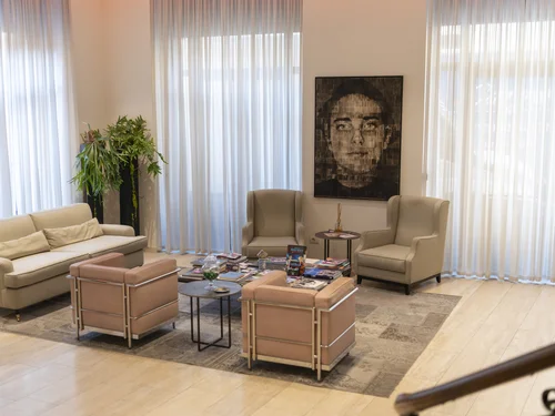 Bright lounge with a sofa, armchairs, coffee tables, magazines and a large portrait