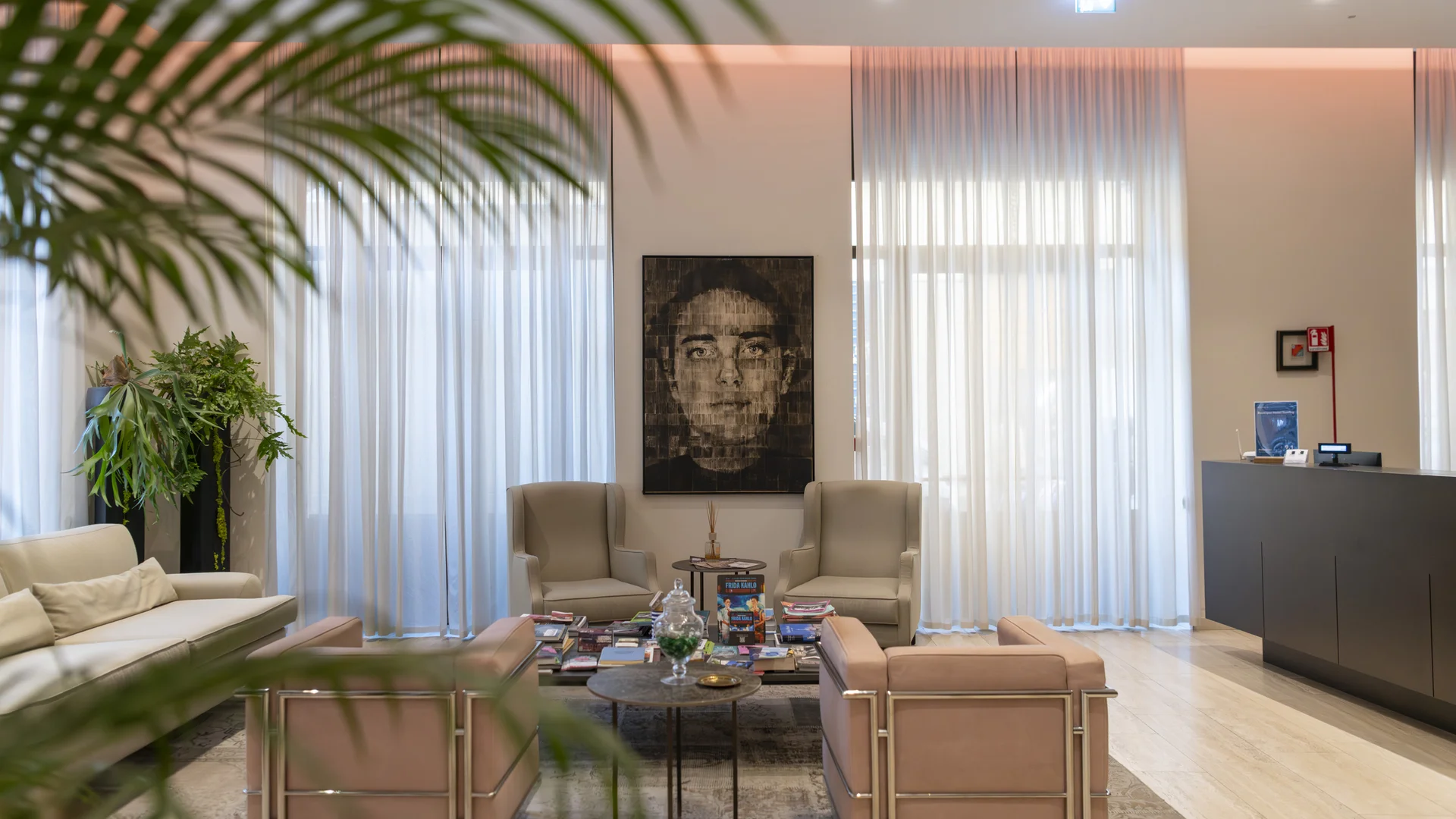 Hotel lounge with sofas, armchairs, coffee table, large windows and indoor plants