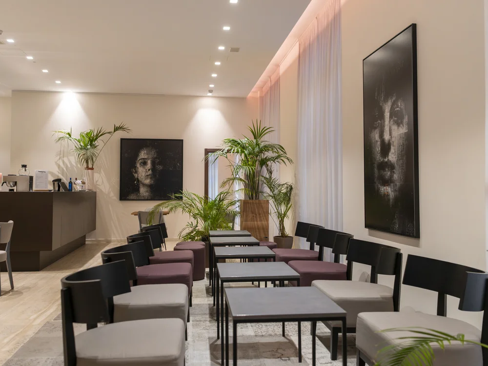 Hotel lounge with armchairs, coffee tables, potted plants and a reception counter