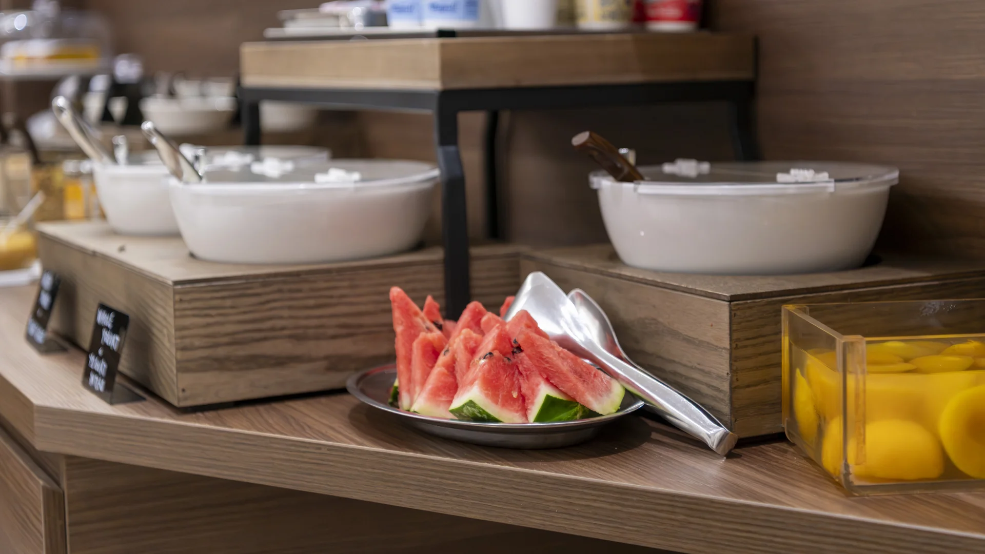 Breakfast buffet with bowls, watermelon slices and yellow fruit