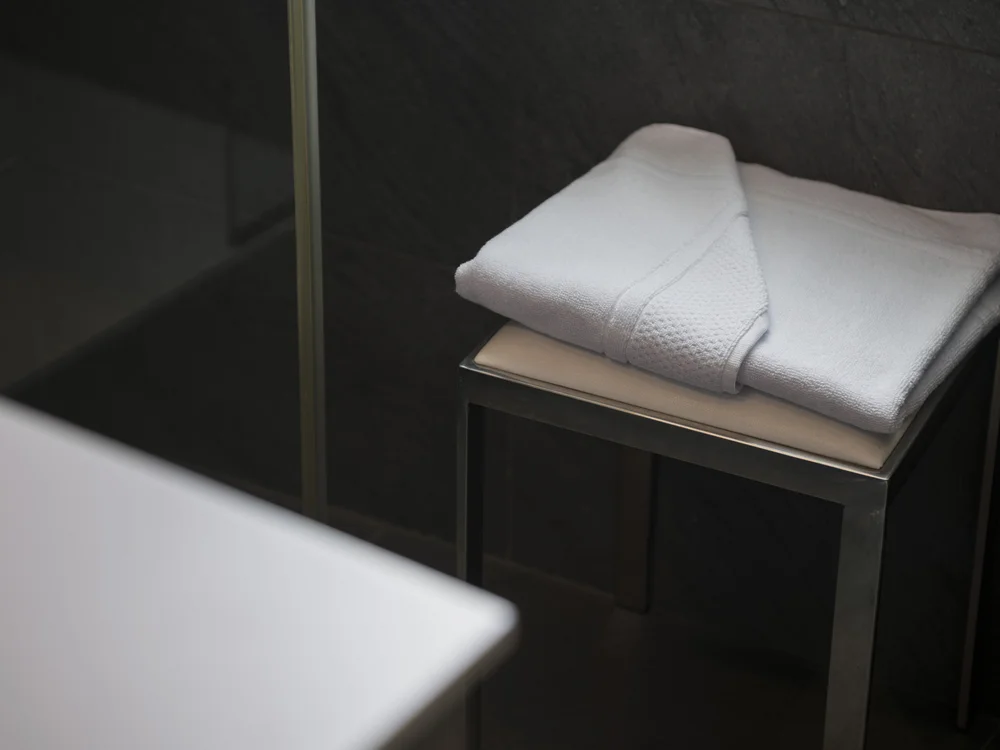 Folded white towels on a small metal stool