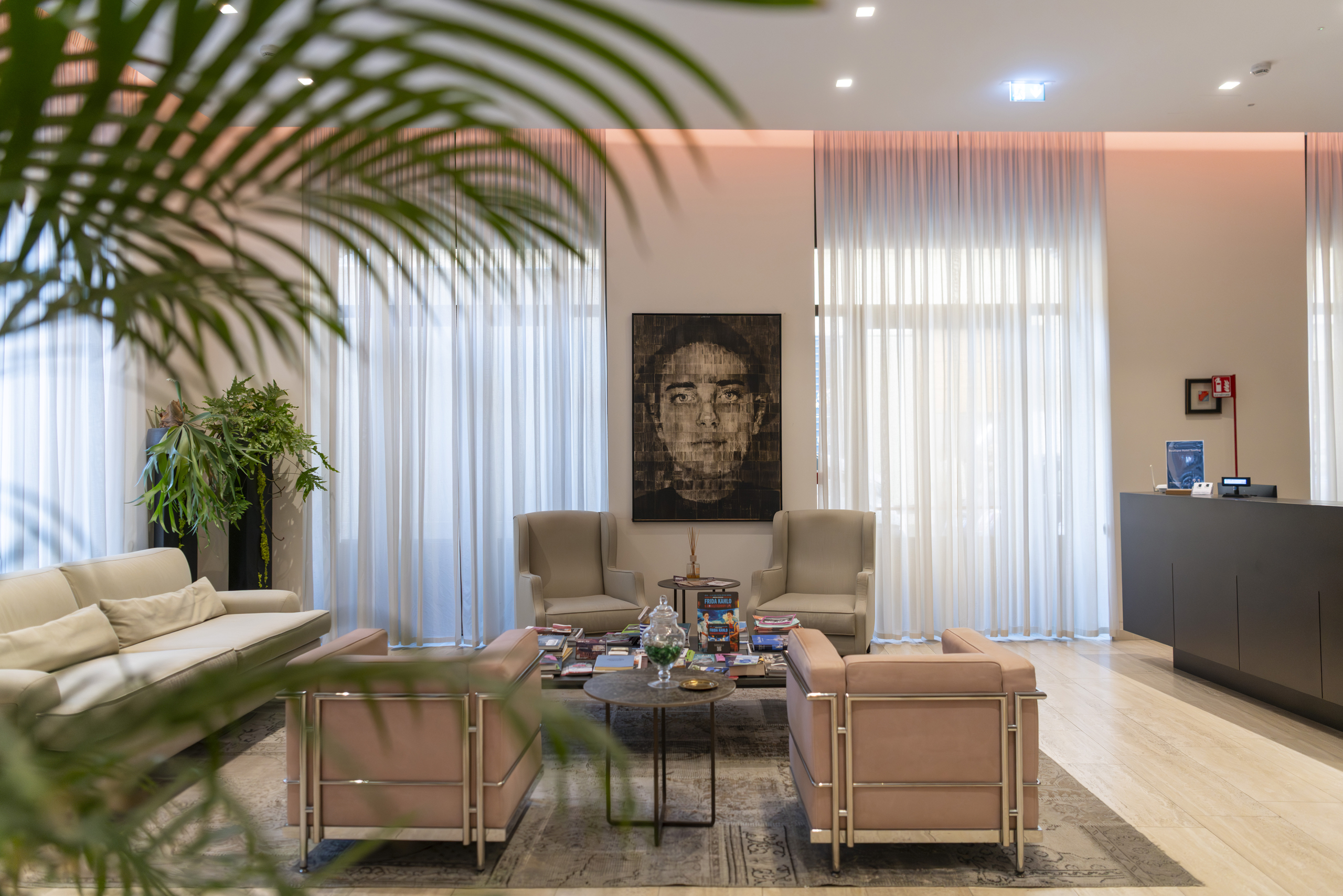 Hotel lounge with sofas, armchairs, coffee table, large windows and indoor plants