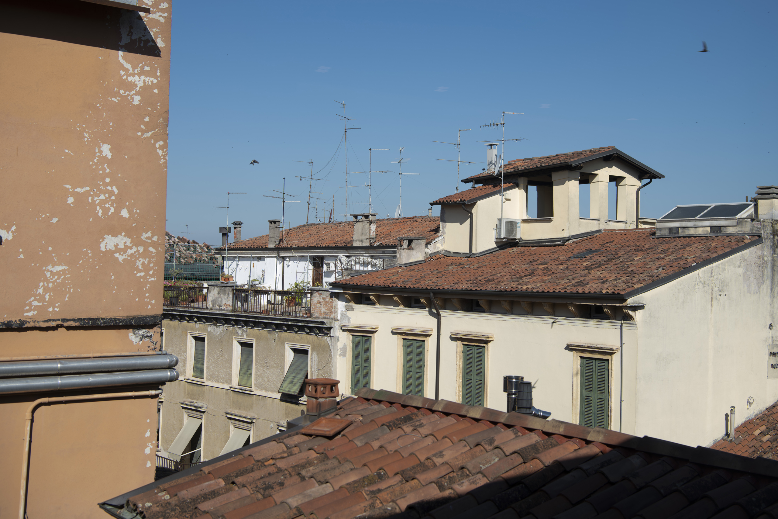 Terracotta rooftops and old buildings with antennas beneath a clear blue sky